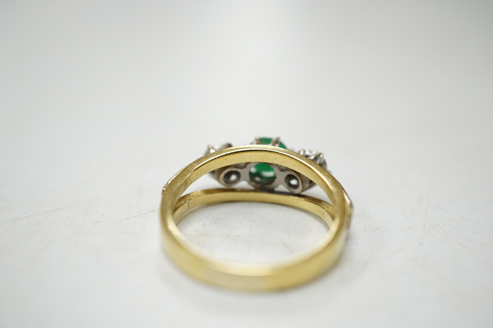 A modern yellow metal, emerald and diamond set three stone ring, size G, gross weight 3.8 grams. Condition - fair